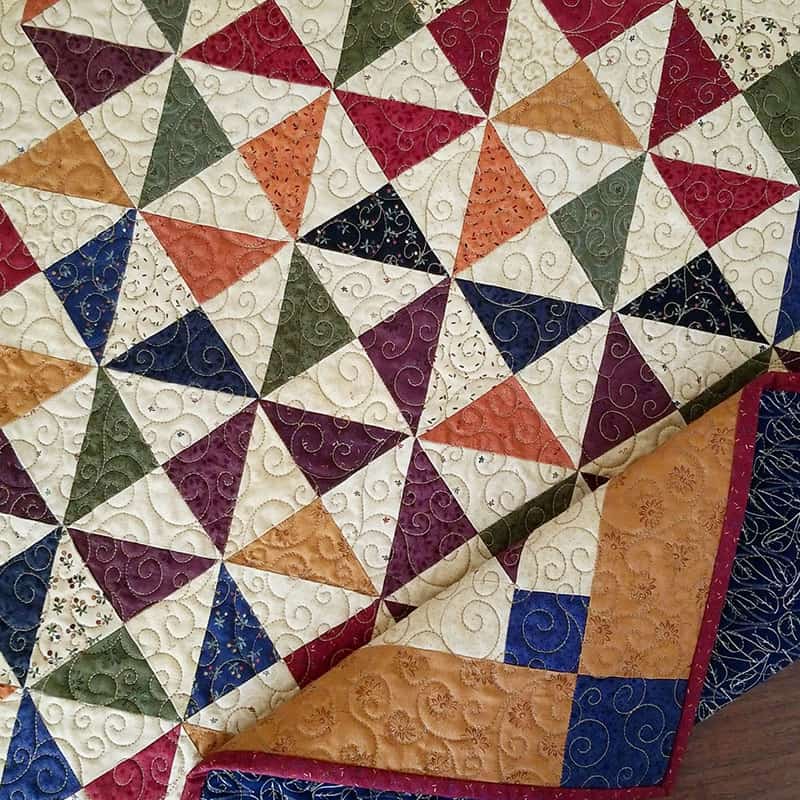 Moda Summer Charm Swap: Charm Square Table Runner by popular quilting blog, A Quilting Life: image of a Moda pattern and Harper's Garden dark fabric charm table runner.