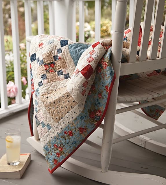 Hometown summer Quilt | Amazing 4th of July Quilts! by popular quilting blog, A Quilting Life: image of a red, white and blue quilt draped over white rocking chair on a front porch.