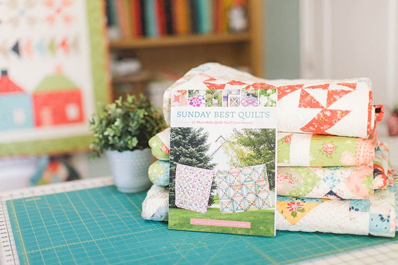 Sunday Best Quilts Sampler Block 12 featured by top US Quilting Blog, A Quilting Life: image of Sunday Best Quilts book and stack of quilts