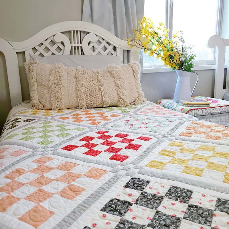 Patchwork Garden 2 Quilt | Patchwork Garden 2 | Jelly Roll Quilt Pattern by popular quilting blog, A Quilting Life: image of a Patchwork Garden 2 quilt on a twin size bed.