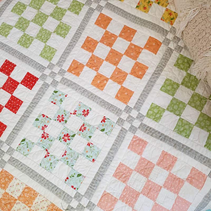 Patchwork Garden 2 | Jelly Roll Quilt Pattern by popular quilting blog, A Quilting Life: image of a Patchwork Garden 2 quilt on a bed.