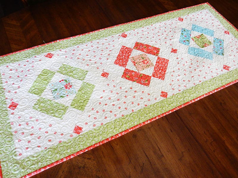 Simply Charming table runner | Simply Charming Charm Pack Runner & Table Topper Quilt Pattern by popular US quilting blog, A Quilting Life: image of a finished Simply Charming table runner.