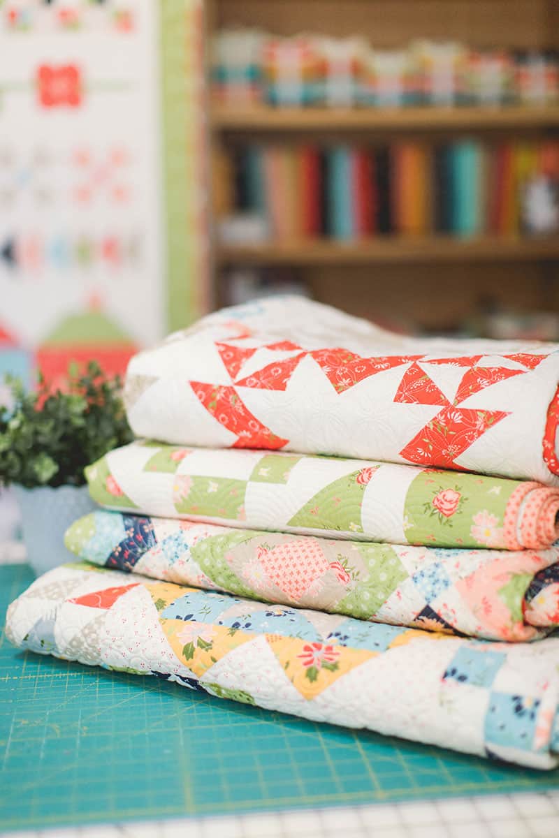 9 Pressing Essentials for Quilters featured by top US quilting blog, A Quilting Life: image of stack of quilts from a quilting life