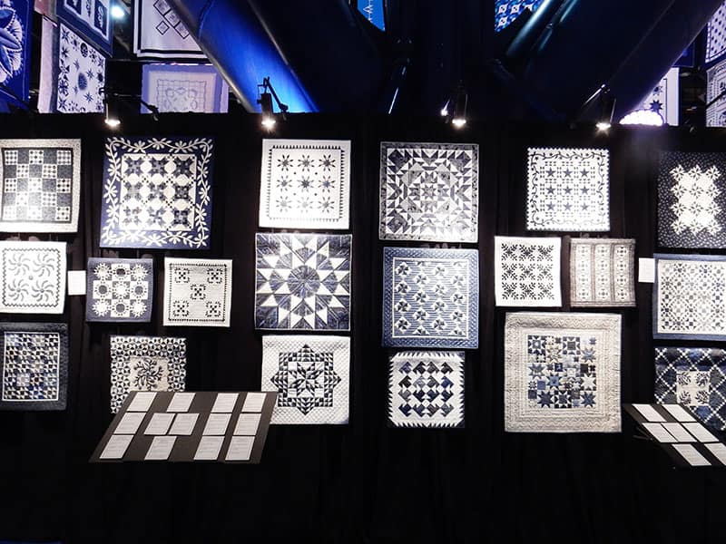 Blue & White Mini Quilts from the Sapphire Celebration Exhibit | More Inspiration from the Houston Quilt Market by popular Utah quilting blog, A Quilting Life: image of mini quilts form the Sapphire collection at the Houston quilting market. 