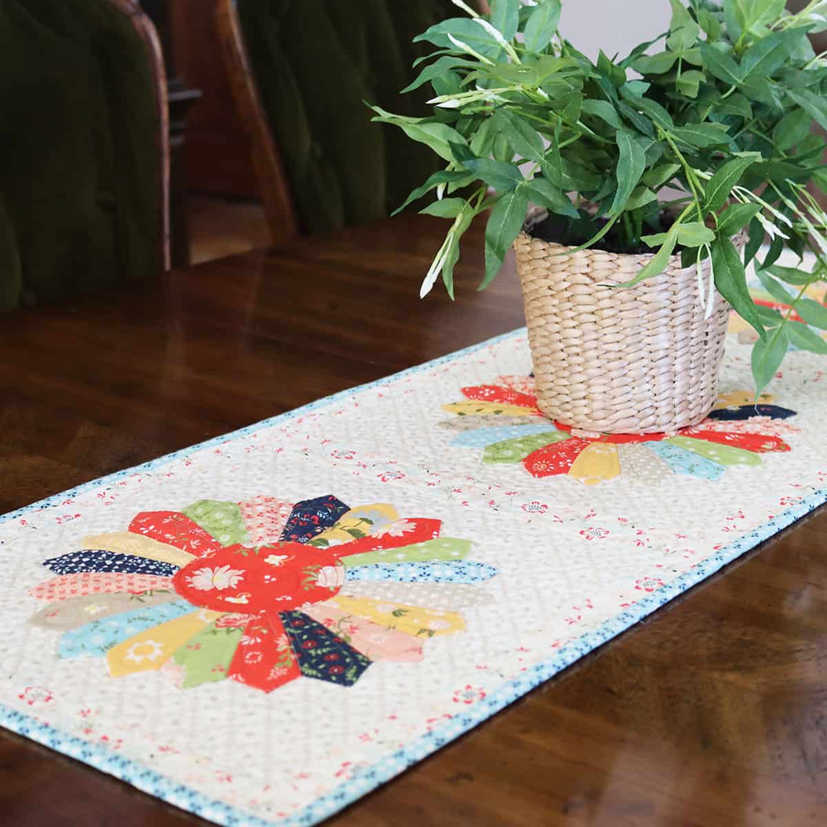 Scrappy Dresden Table Runner quilted on a table with plant.