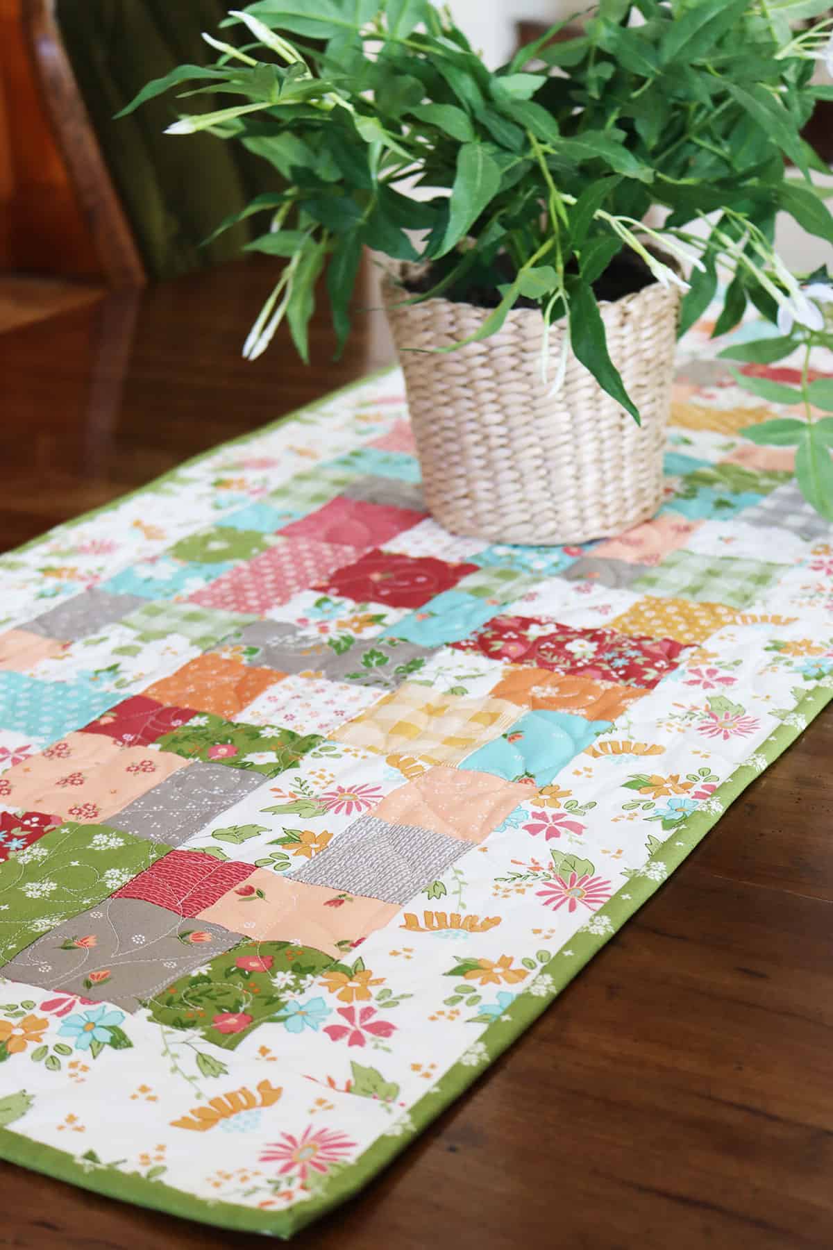 Quilted patchwork table topper with plant on table.