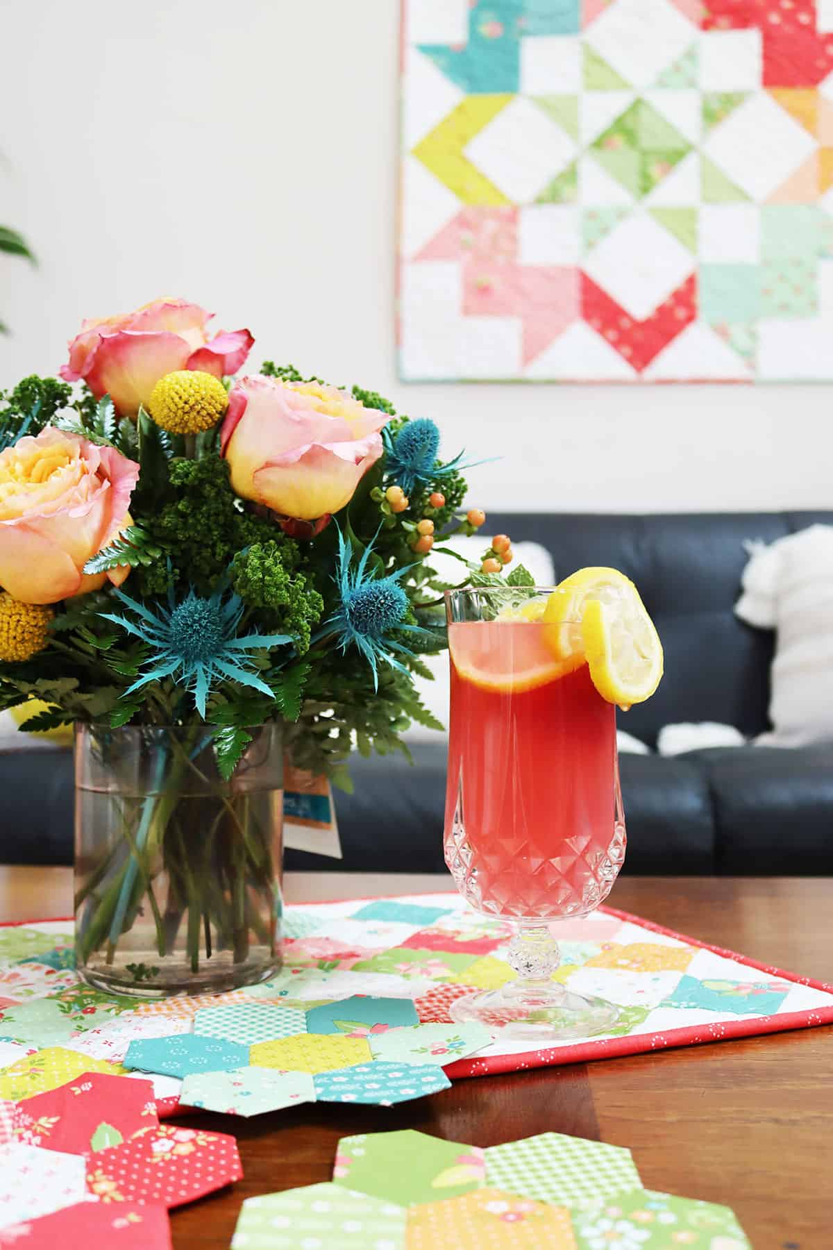 Flowers with glass of lemonade with quilt on the wall and on the table