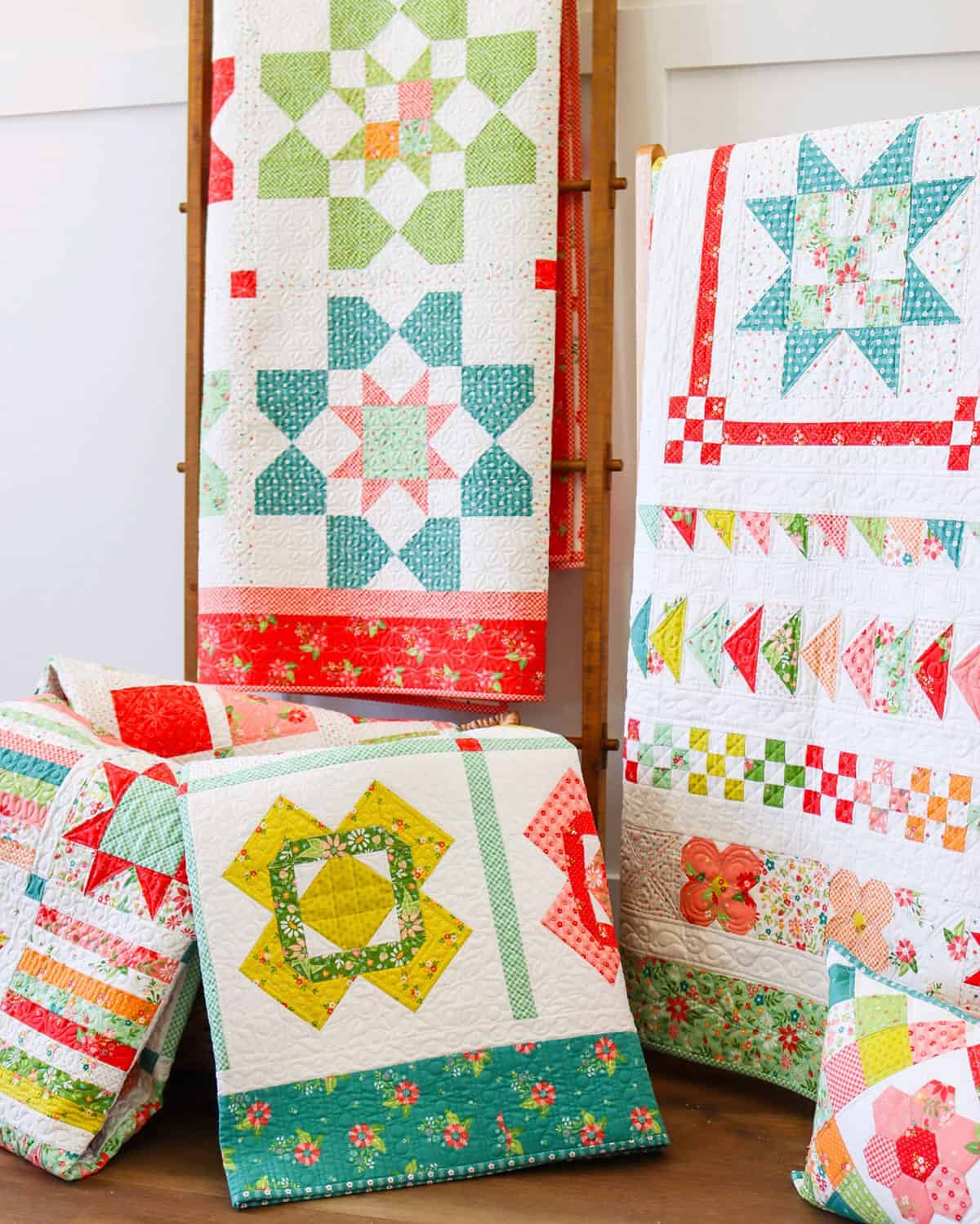 quilts on ladders and in a basket with brightly colored fabrics