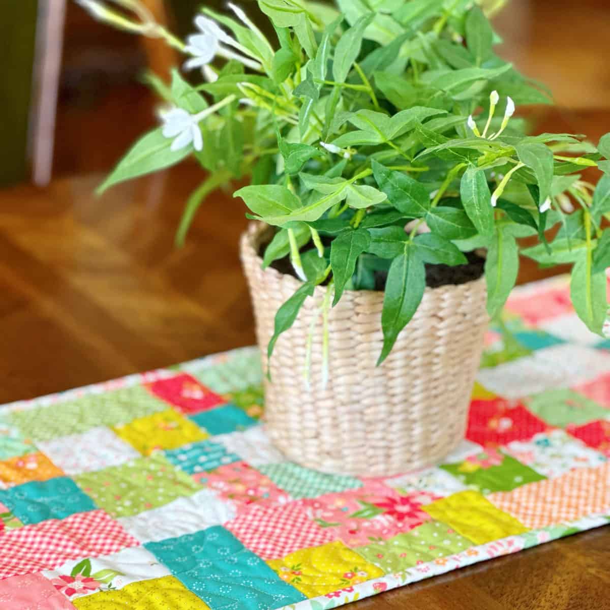 Table runner in bright Strawberry Lemonade fabrics with plan in a wicker basket on top.