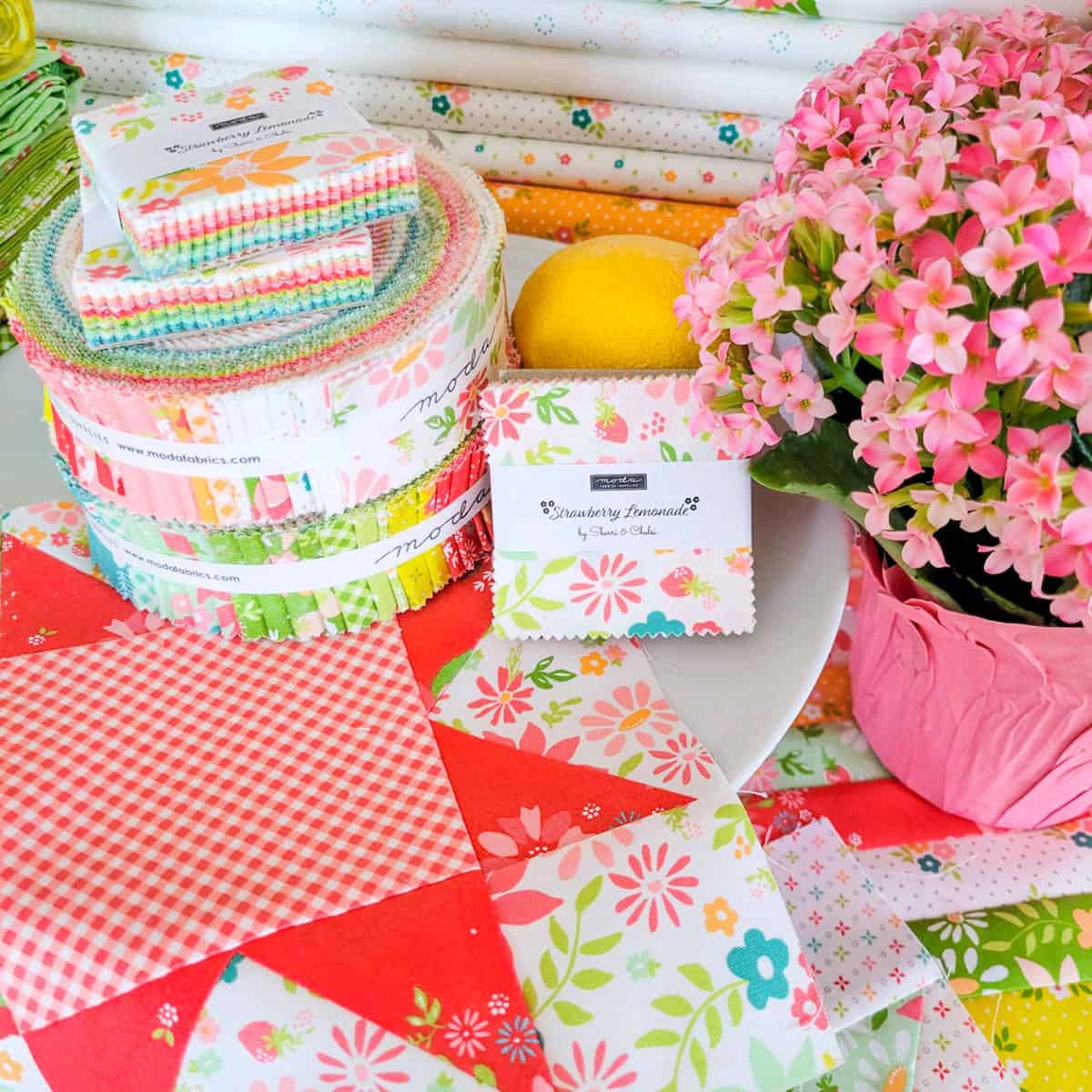 Brightly colored fabrics, quilt block, and potted flower arrangement.