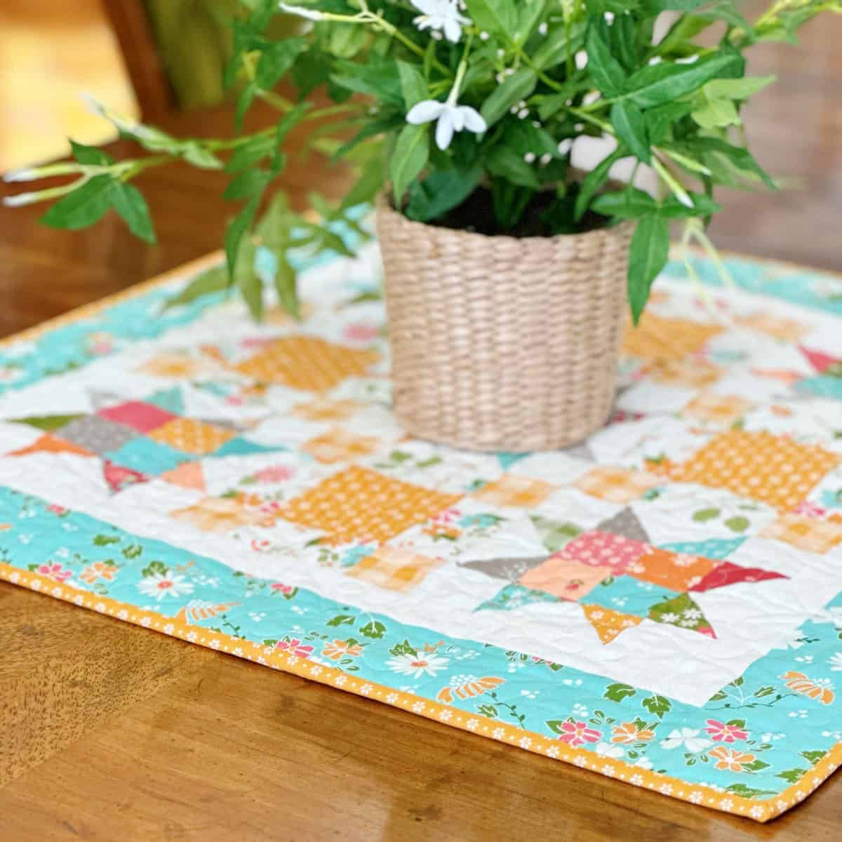 Quilted patchwork table topper in bright fall colors with potted plant on top.
