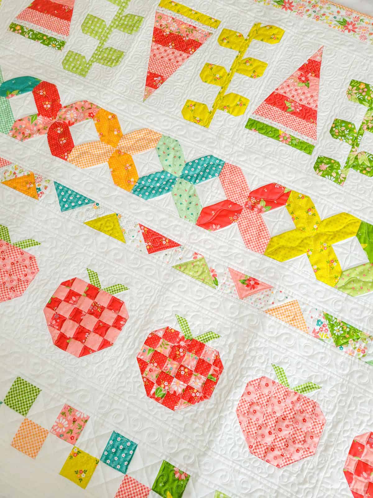 Brightly colored quilt wall hanging with watermelon, vines, strawberries, and patchwork designs.