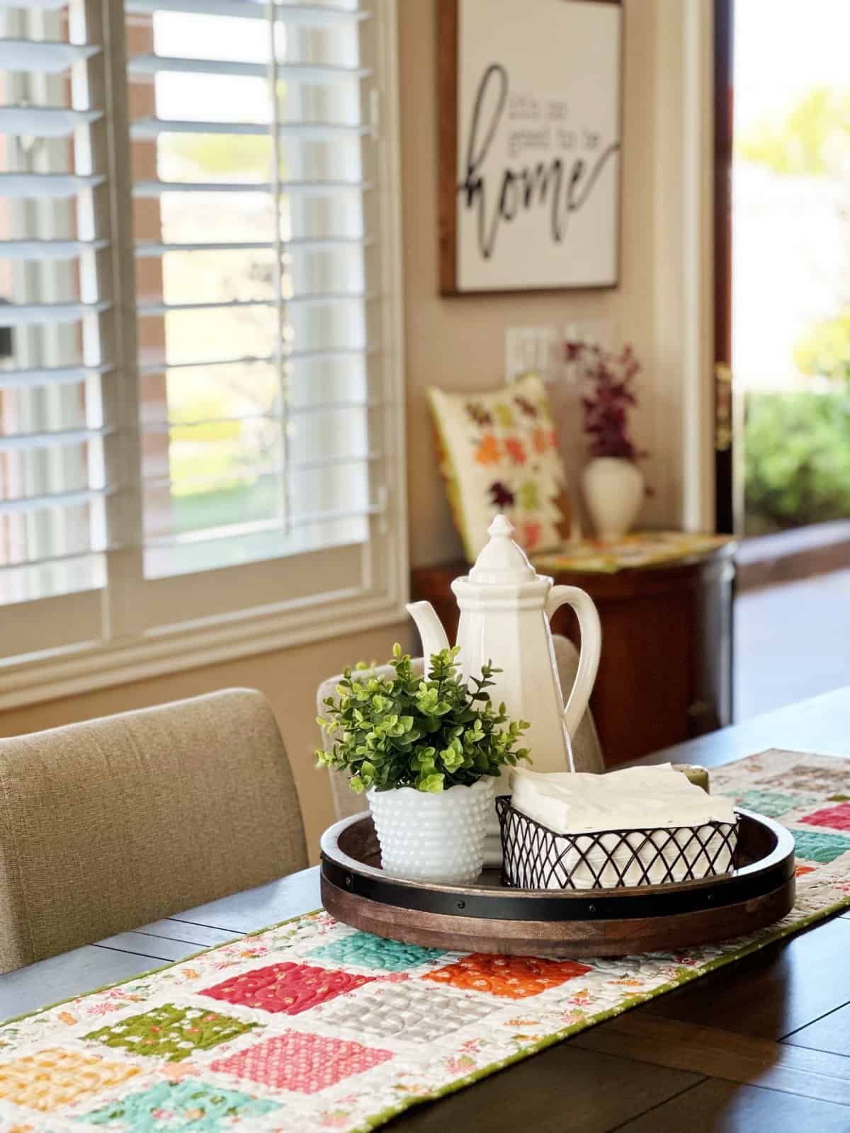 Patchwork quilted runner with pitcher, plant, and napkin holder on table