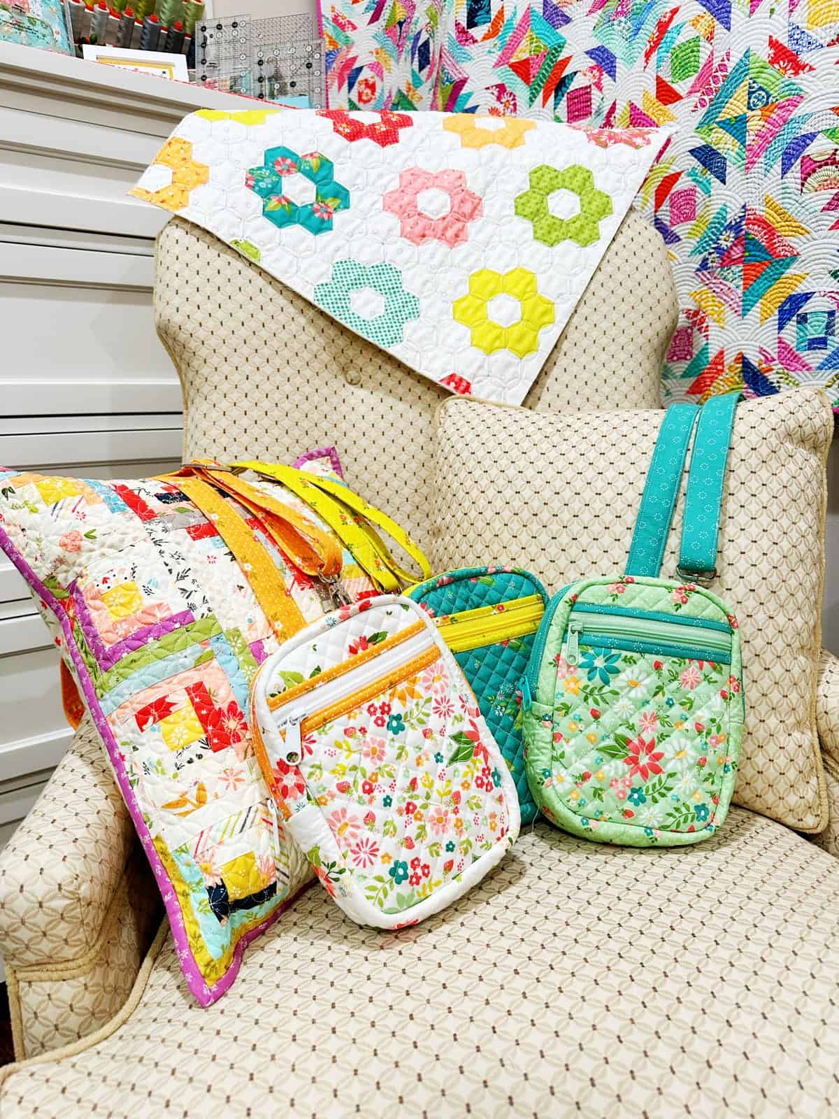 Quilted Crossbody Bags on a chair with patchwork log cabin pillow and pineapple quilt on the wall.