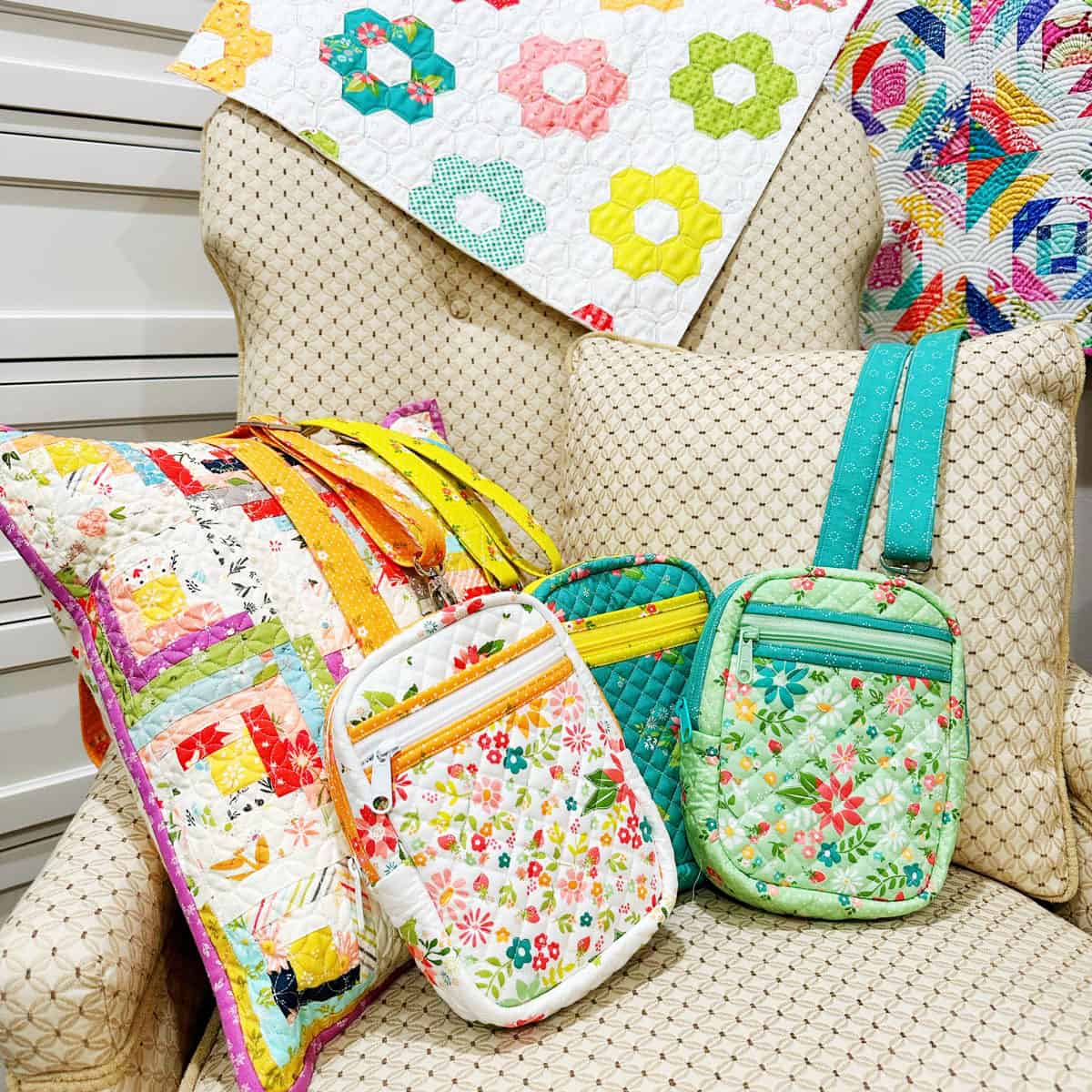 Quilted Crossbody Bags on a chair with patchwork log cabin pillow and pineapple quilt on the wall.