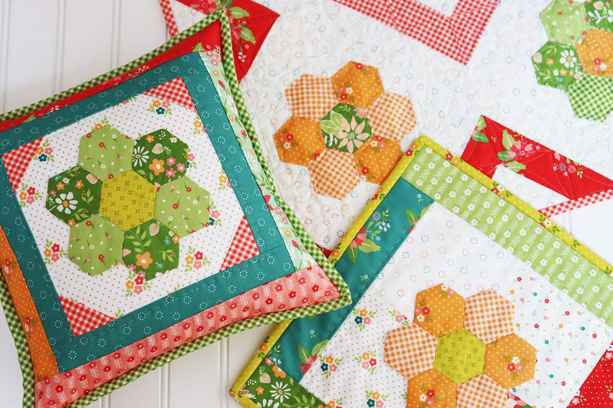 Pillow, table topper, and mug rug featuring Grandmother's Flower Garden blocks in bright colors