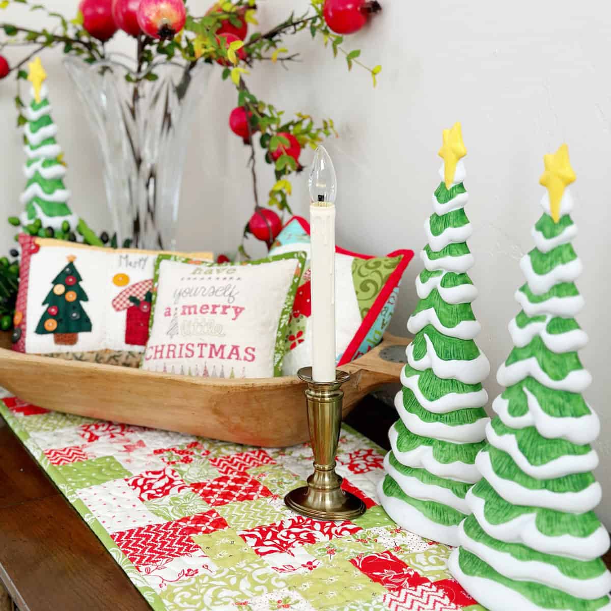 Christmas pillows in bowl with ceramic Christmas trees and candle