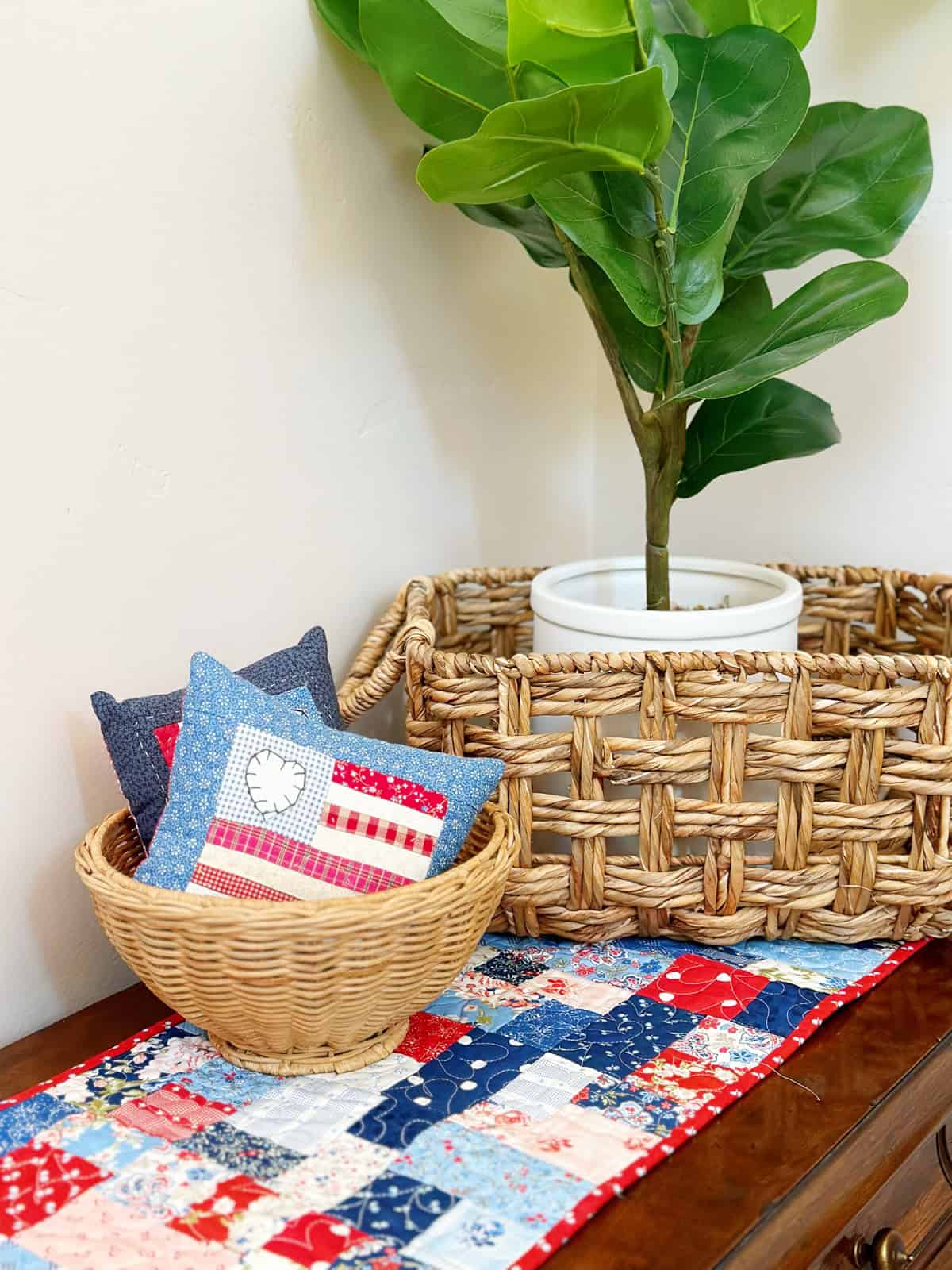 Scrappy Table Runner with plant and basket with patriotic pillows.