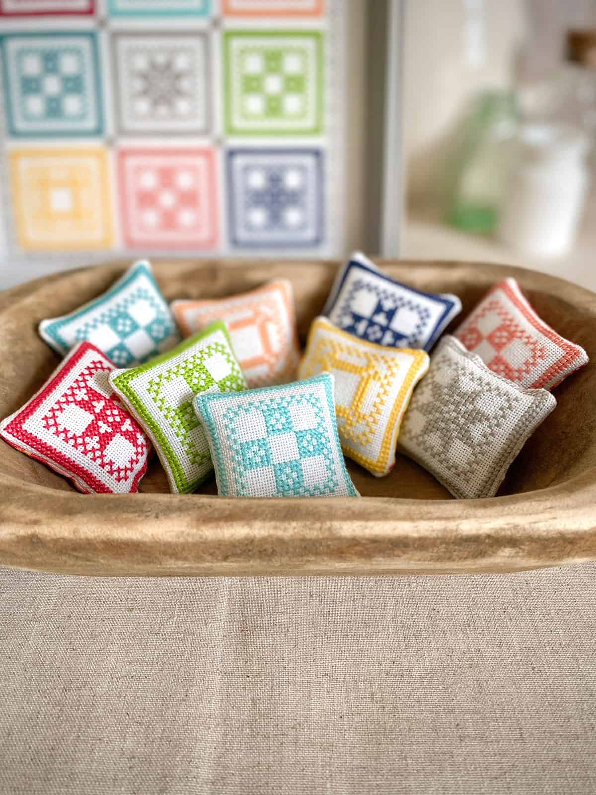 Mini cross stitch pillows or pincushions inspired by the Block Party quilt pattern by Sherri of A Quilting Life