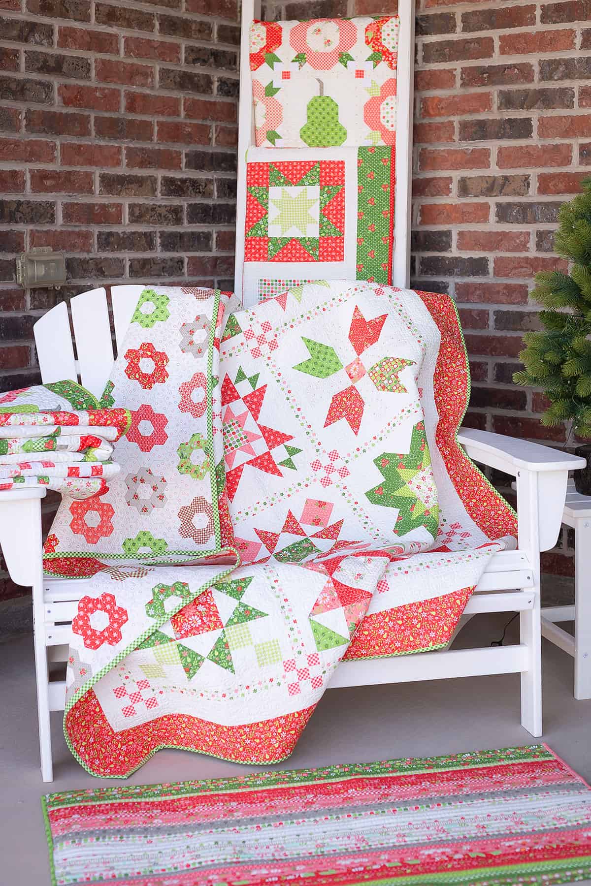 Bench on a porch with Christmas quilts and a Christmas rug from Sherri at A Quilting Life