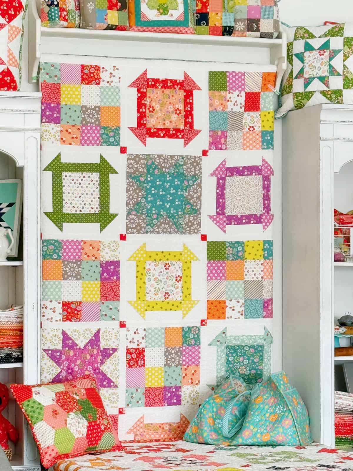 Happy Go Lucky 2 Quilt in Laguna Sunrise Fabrics on the wall in the A Quilting Life studio