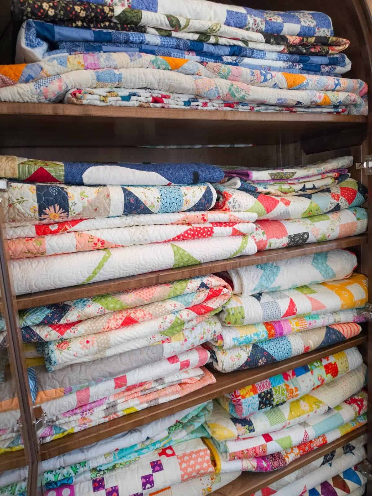 Quilts in a cupboard by Sherri McConnell of A Quilting Life